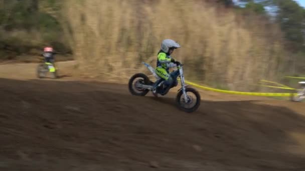 Un garçon dans un casque et un équipement de protection monte sur une moto électrique — Video