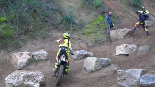 Ung flicka hoppar på en stor sten under en motorcykel rättegång. — Stockvideo