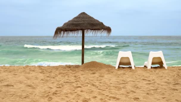 Een stroparasol en twee ligstoelen op de oceaan. vakantie concept voor twee — Stockvideo