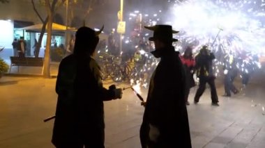 Lucifer kostümlü ve boynuzlu şapkalı bir adam elinde meşale tutuyor.