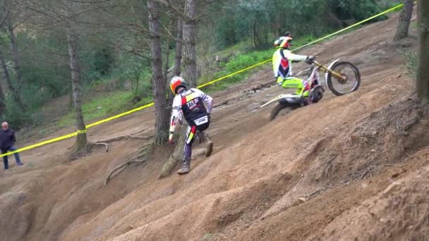 Motociclista conduce una montaña empinada cubierta de arcilla en una motocicleta para una prueba . — Vídeo de stock