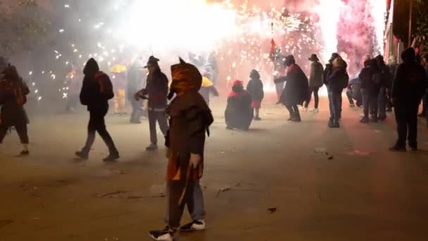 People in devil costumes dance at night on the street with fireworks — Stock Video