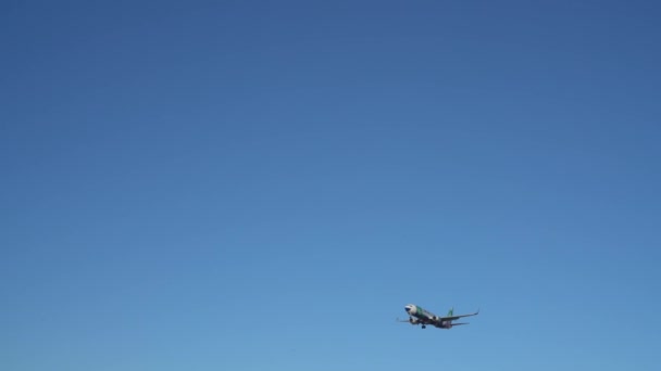 Multi-colored plane flies over the camera against the blue sky. — Stock Video