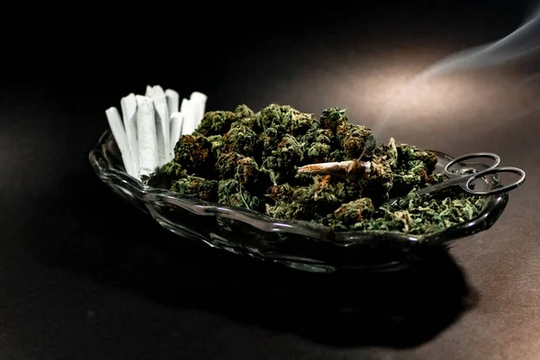 Klasszikus üvegedény marihuána rügyekkel, ollóval és egy tucat ízülettel. — Stock Fotó