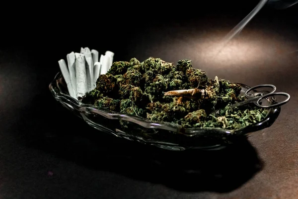 Klasszikus üvegedény marihuána rügyekkel, ollóval és egy tucat ízülettel. — Stock Fotó