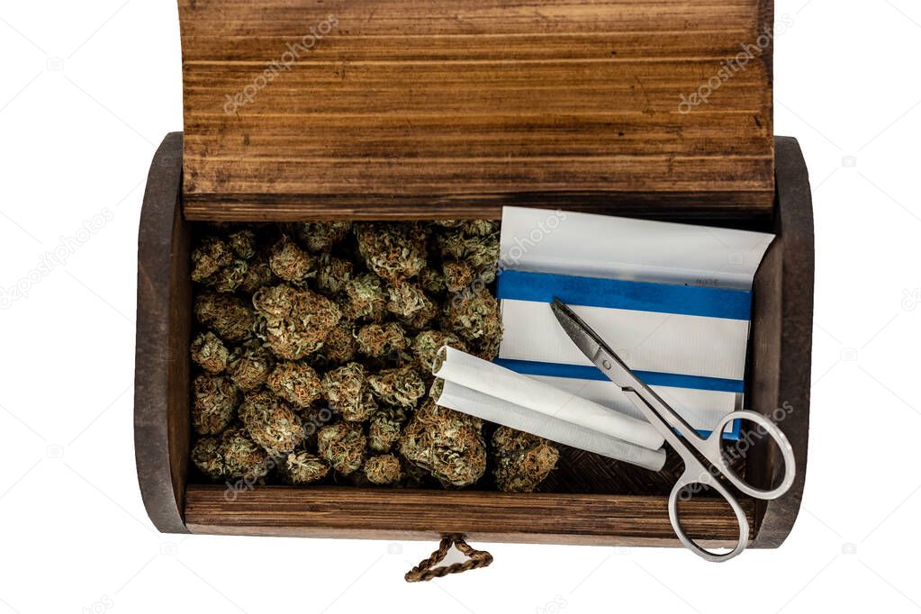 A wooden stash box half filled with green marijuana buds covered