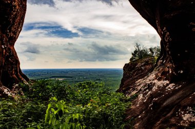 İki büyük kaya oluşumundan etkileyici bir manzara çevreye benzer bir mağara yaratır. Kuzey Doğu Tayland 'da Phu dağının yamacından aşağı orman tepe örtüsünün tepesindeki ağaçlara bakıyorum..