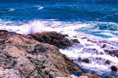 Beyaz sular Promthep Burnu, Phuket Tayland 'ın güneyindeki kayalık kıyı şeridine çarpar.