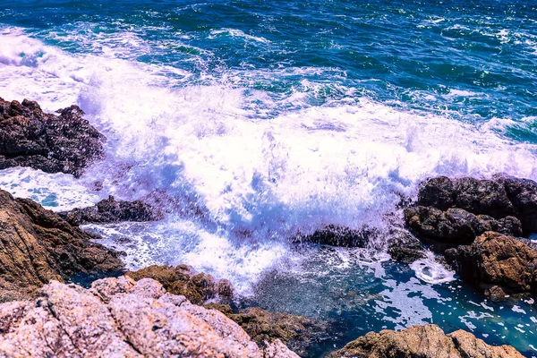 Beyaz sular Promthep Burnu, Phuket Tayland 'ın güneyindeki kayalık kıyı şeridine çarpar.