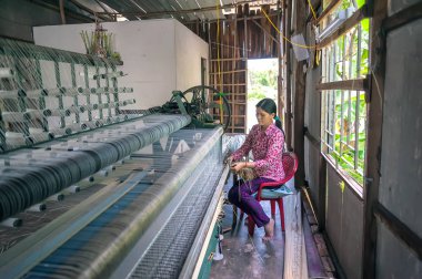 Tien Giang-Vietnam: genç kadın uzun Dinh Tien Giang il, Vietnam makine tarafından geleneksel hasır dokuma. Mat yatağın yaymak için kullanılan her aile için gerekli bir öğedir.