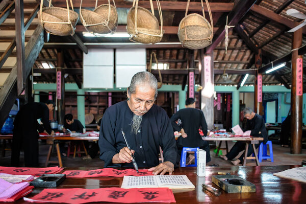 VUNG TAU- VIETNAM: Old man with traditional black costume, white beard drawing calligraphy ancient distich in Long Son district of Ba Ria Vung Tau province, Vietnam. 