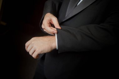 Smokin giymiş yakışıklı damat düzeltmeleri kol düğmesi.