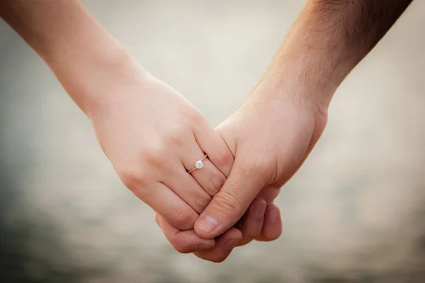 Νέοι πρόσφατα παντρεμένος ζευγάρι πιασμένοι χέρι χέρι με ένα υπόβαθρο στη λίμνη. — Φωτογραφία Αρχείου