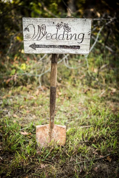 Rustic wedding arrow sign on a shovel.