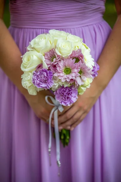 Beautiful floral bouquet being held by bridesmaid in a purple dr — Stock Photo, Image