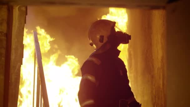 Statečný hasič sestupuje na hořící schodiště. Rozhlížel se kolem prohlídku budovy. Otevřený oheň na pozadí.