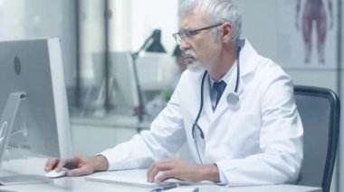 Kıdemli doktor ve masaüstü bilgisayarlarda çalışma Yardımcısı close-up. Parlak oturan Office yaktı.