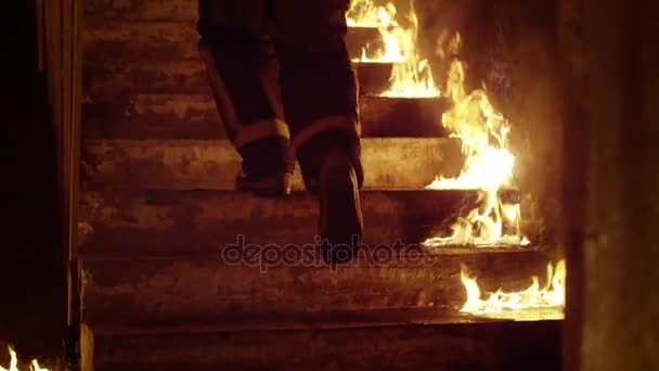 Gros plan des jambes d'un pompier montant les escaliers en flammes. Bâtiment est sur le feu Les flammes nues sont vues partout. Mouvement lent .
