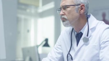 Kişisel bilgisayarınızda çalışan beyaz saçlı Doktor yakın çekim portre. Ofisinin parlak olduğunu ve ışık.