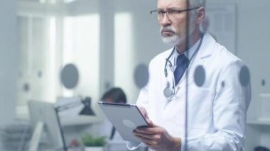 Kıdemli Doktor hastanın tanı ve bir Tablet bilgisayarda yazarak düşünmeye. Parlak ve Modern ofisinin olduğunu.