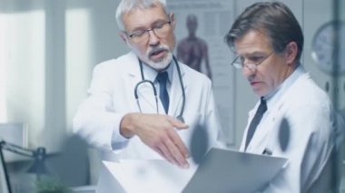 İki uzman doktor hastanın günlük tartışıyor. Her ikisi are kıdemli ve deneyimli. Onların ofis Modern ve saygıdeğer görünüyor.