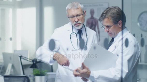 Dva lékaři odborné diskuse o pacienta Log. Oba jsou starší a zkušený. Jejich kancelář vypadá moderní a seriózní.