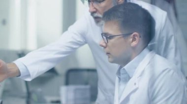 Üst düzey tıbbi uygulayıcısı ve genç meslektaşı tıbbi durumları tartışmak. Kendi ofis parlak bakıp Moder oldu. Ağır çekimde atış.