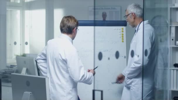 Två specialistläkare diskutera hälsofrågor och medicinsk drog prov resultaten över Whiteboard. — Stockvideo