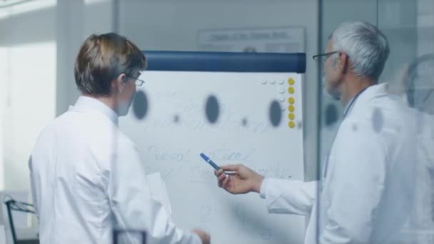 Dois médicos especialistas discutindo questões de saúde e resultados de ensaios de drogas médicas sobre Whiteboard . — Vídeo de Stock