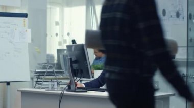 Meşgul mühendis Bürosu. Şef, masanın üstüne yalan bazı teknik bileşenleri masasında, çalışan mühendis. Arka planda onun masasında asistanı çalışır.