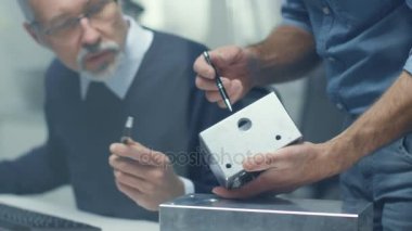 İki üst düzey mühendisler önemli teknik bileşenleri, onları birleştirmek tartışmak. Her ikisi are deneyimli ve bilge. Onların ofis Modern ve parlak görünüyor.