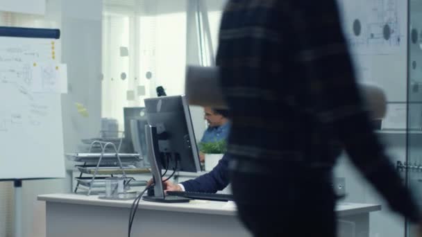 多忙なエンジニア局。チーフ エンジニアは働く彼の机で彼の机の上に横になっているいくつかの技術的なコンポーネント。バック グラウンドで彼の机に彼のアシスタントの作品. — ストック動画