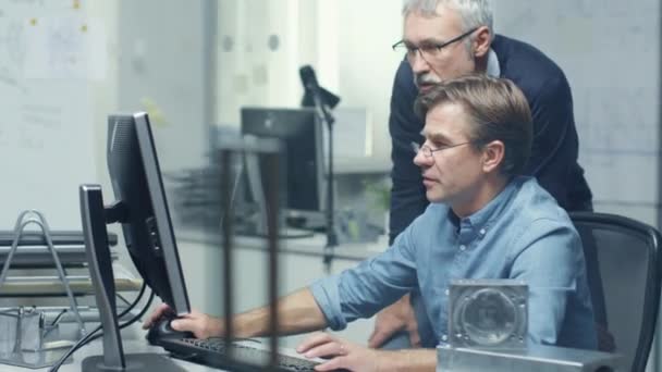 V práce inženýrská kancelář dva vysocí inženýrů diskuse o technických problémech přes osobní počítač. Jejich kancelář vypadá minimalistický a moderní. — Stock video