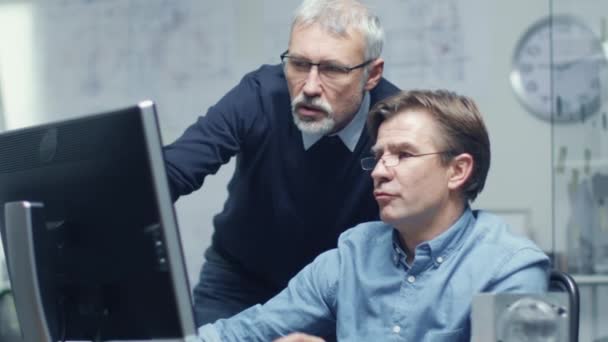 In Busy Engineering Bureau Two Senior Engineers Discussing Technical Issues over Personal Computer (en inglés). Su oficina parece minimalista y moderna. Disparo en cámara lenta . — Vídeos de Stock