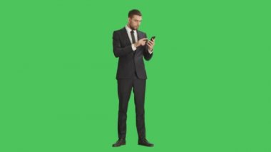 Yakışıklı işadamı Smartphone bir eliyle tutarak ve hareketleri ile başka bir dokunmadan Swiping yapma düşük ihtimal. Tablet ve arka plan yeşil ekran vardır.