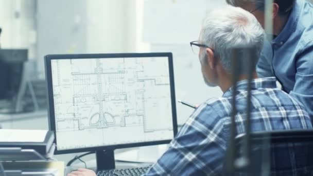 Dois Engenheiros de Arquitectura Sénior a trabalhar com a construção de plantas num computador pessoal. Eles discutem ativamente vários planos e esquemas . — Vídeo de Stock