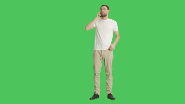 Lange Aufnahme eines gutaussehenden, lässigen Mannes, der am Telefon spricht. Aufnahme mit grünem Hintergrund. — Stockvideo