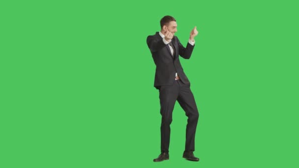 Длинный снимок красивого улыбающегося бизнесмена, танцующего, делающего жест на пальцах и получающего удовольствие. Фон - зеленый экран . — стоковое видео