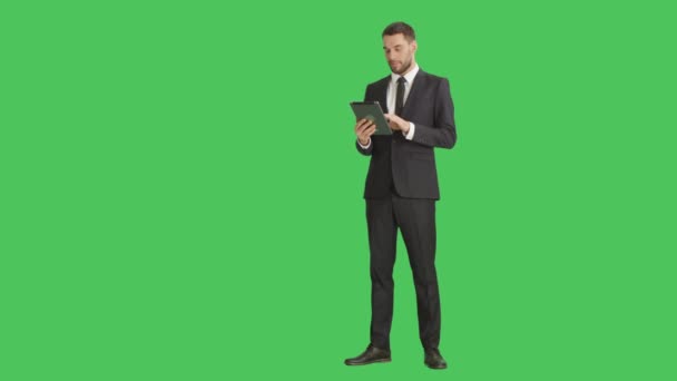 Long Shot of a Handsome Businessman Holding Tablet Computer with One Hand and Making Swiping Touching Gestures with Another. Tableta y fondo son pantalla verde . — Vídeo de stock