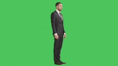 Yakışıklı ciddi düşünen işadamı ve onun etrafında dönen kamera düşük ihtimal. Yeşil ekran arka plan üzerinde tüm çekim.