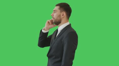 Telefonda konuşurken yakışıklı bir ciddi düşünen işadamı orta vurdu. Onun arka planı yeşil ekranıdır.