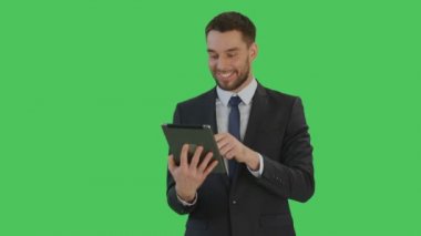 Gülümseyen yakışıklı işadamı orta atış hareketleri bir Tablet bilgisayarda Swiping yapar. Yeşil ekran arka plan olduğunu.