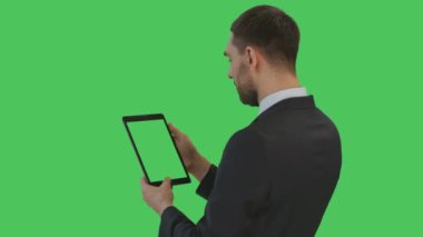 Orta Backview bir kadeh bir Tablet bilgisayarda bir işadamı okuma. Tablet ekran ve arka plan yeşil ekran vardır.