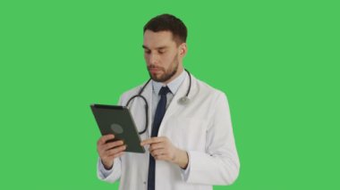 Orta atış hareketleri bir Tablet bilgisayarda Swiping gülümseyen bir yakışıklı doktor yapar. Yeşil ekran arka plan olduğunu.