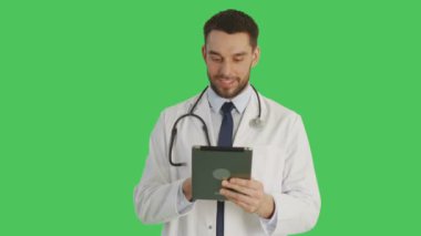Orta atış hareketleri bir Tablet bilgisayarda Swiping gülümseyen bir yakışıklı doktor yapar. Yeşil ekran arka plan olduğunu.