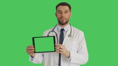 Gülümseyen bir doktor yatay yeşil ekran Tablet bilgisayarınızla tutan orta vurdu. Arka planda yeşil ekran.