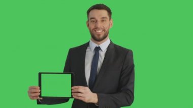 Orta atış yatay yeşil ekran Tablet bilgisayarınızla tutan gülümseyen yakışıklı işadamı. Arka planda yeşil ekran.