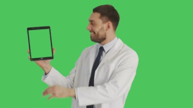 Yakışıklı doktor doz orta / Tablet bilgisayar tek elle tutarak ve dokunmadan Swiping yapım bilim adamı jestleri başka bir ile. Tablet ve arka plan yeşil ekran vardır.
