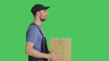 Profil karton kutunun içinde teslim yakışıklı bir yükleyici orta çekim. Yeşil ekran arka plan ile vurdu.