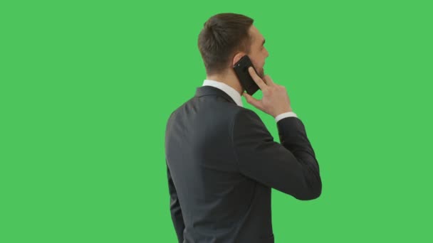 Μεσαίο πλάνο του ένας όμορφος άνθρωπος μιλάει στο τηλέφωνο ενώ κάμερα περιστρέφεται γύρω από τον. Γυρίστηκε σε μια πράσινη οθόνη φόντου. — Αρχείο Βίντεο